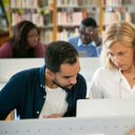 ethnic bearded male student preparing study task and explaining project details to teacher in university library